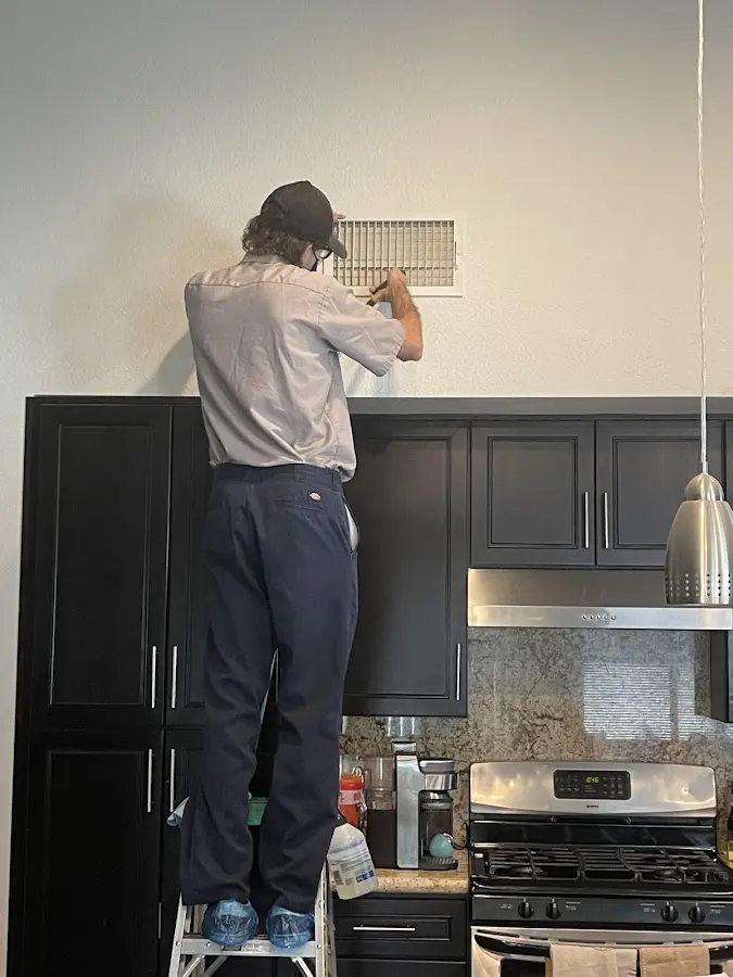 Technician inspecting an air vent during HVAC service in Sylacauga